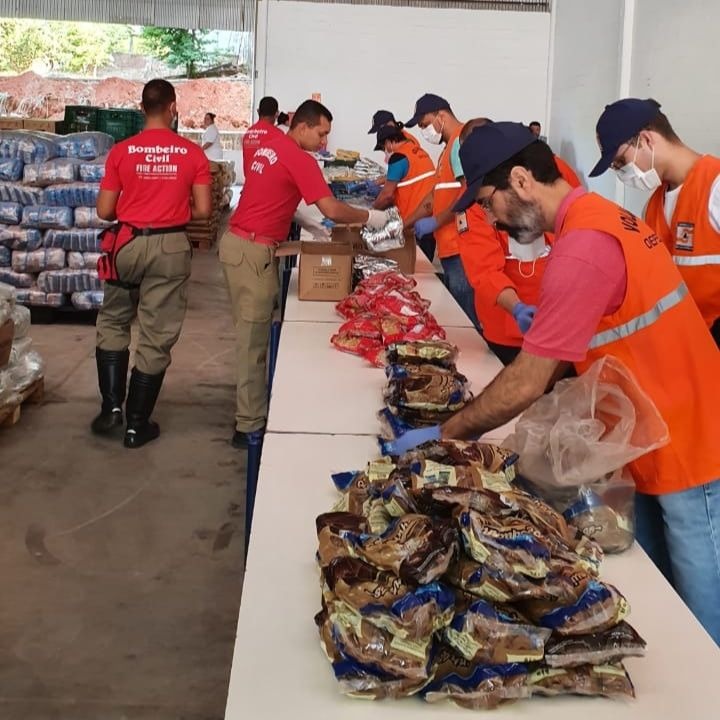 Bombeiros civis ajudando na montagem dos 14 mil kits de alimentação escolar